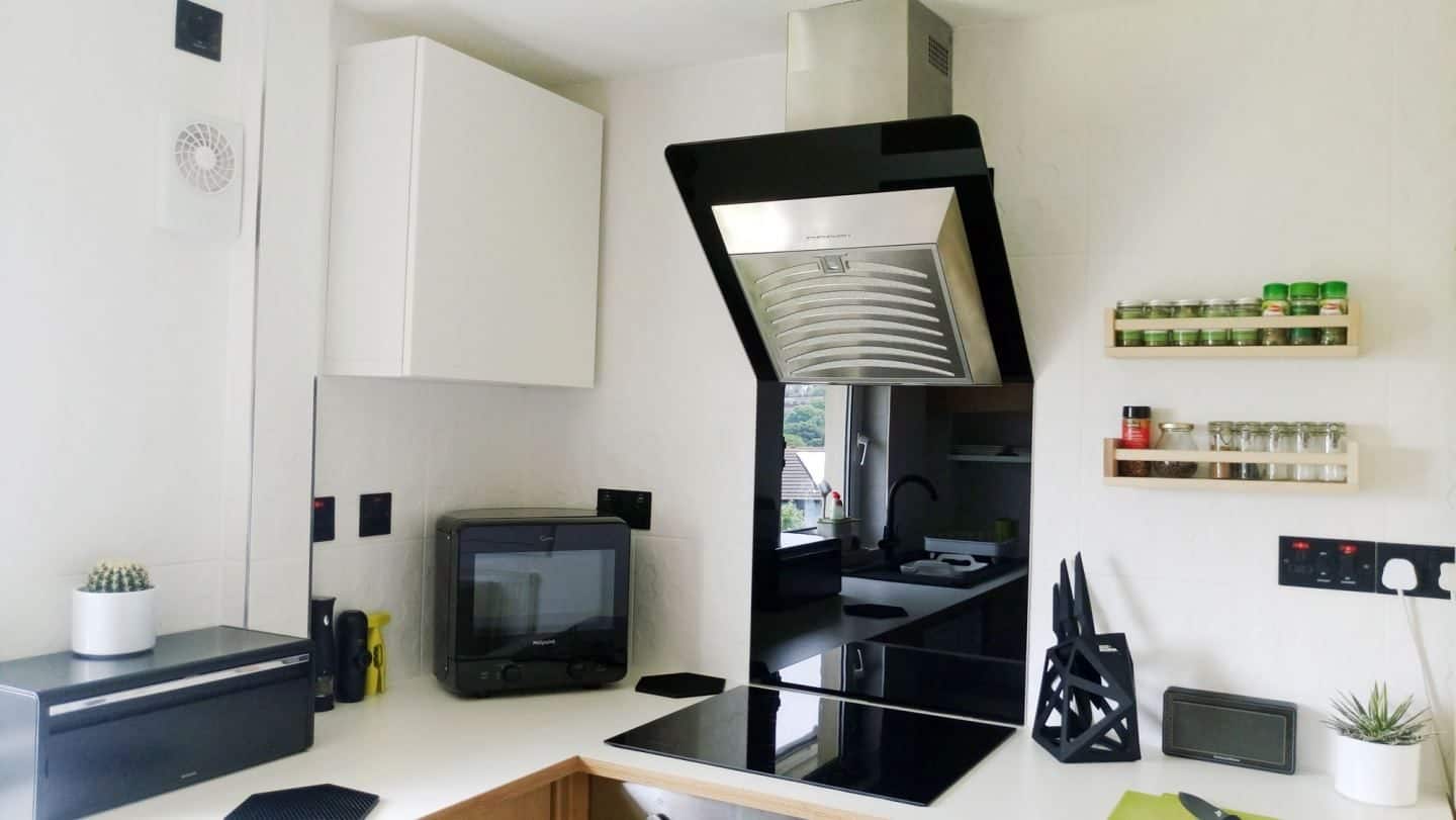 A modern kitchen with white tiles, white worktop and black accents.